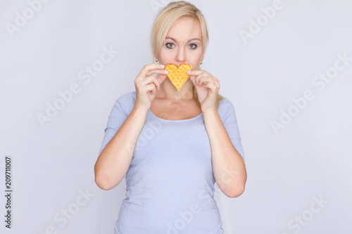 Happy blond woman holding in hands and showing belgian waffles