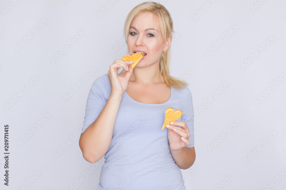 Happy blond woman holding in hands and showing belgian waffles Happy blond woman holding in hands and showing belgian waffles