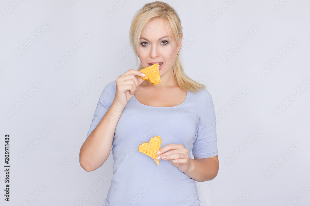 Happy blond woman holding in hands and showing belgian waffles Happy blond woman holding in hands and showing belgian waffles