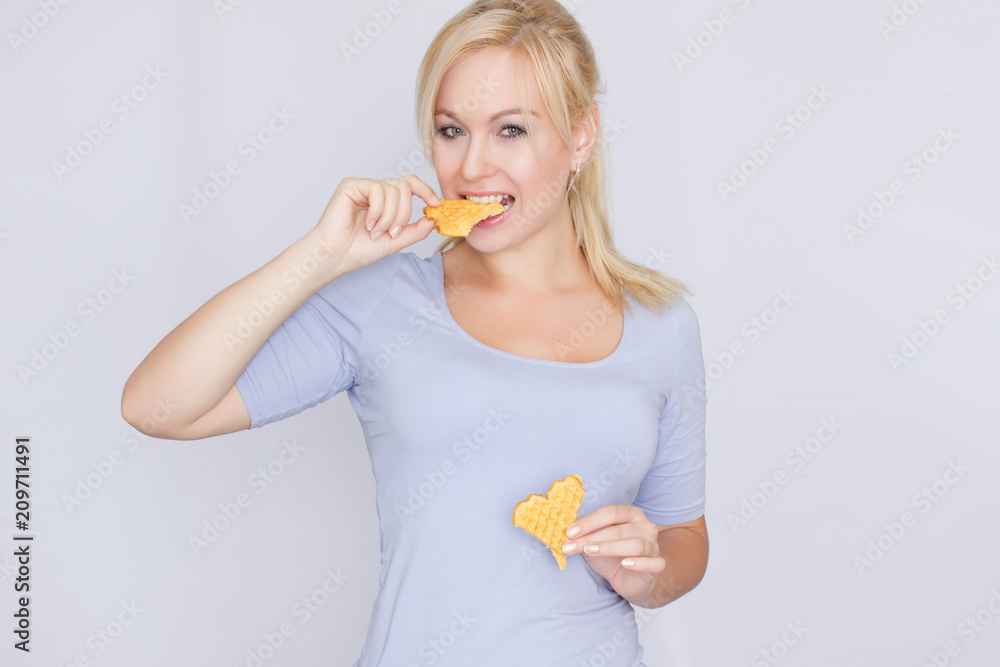 Happy blond woman holding in hands and showing belgian waffles Happy blond woman holding in hands and showing belgian waffles