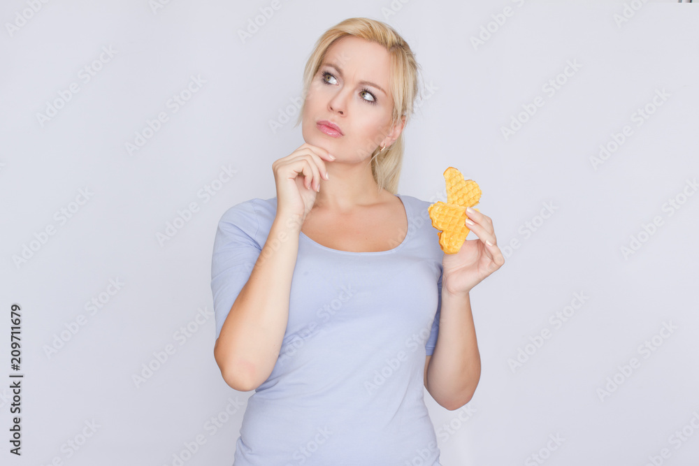 Happy blond woman holding in hands and showing belgian waffles Happy blond woman holding in hands and showing belgian waffles