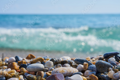 Stones on the beach with blurred sea water and horizon on a background.