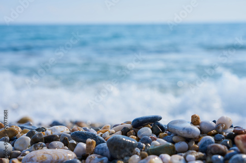 Stones on the beach with blured sea water and horizon on a background. 