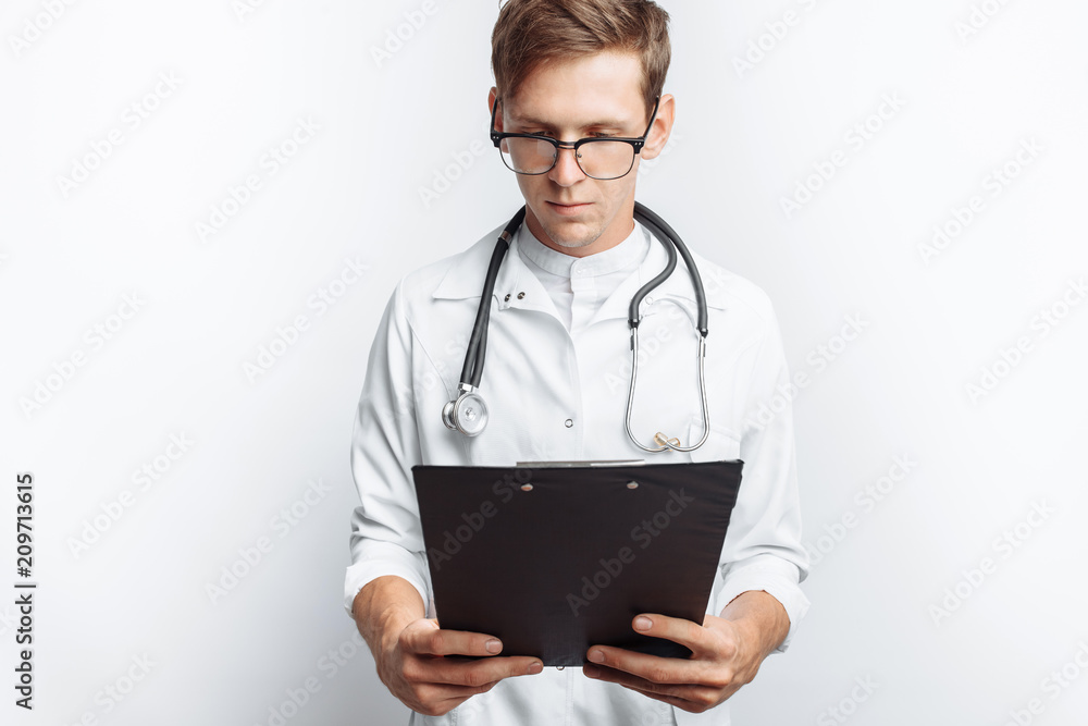 The doctor makes notes in the documents, a young student with a folder in his hands, on a white background The doctor makes notes in the documents, a young student with a folder in his hands, on a white background