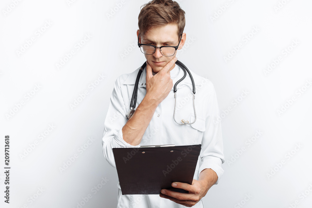 Thoughtful doctor, looking at the documents, and makes notes in the documents, a young student with a folder in his hands, on a white background, for advertising and insertion Thoughtful doctor, looking at the documents, and makes notes in the documents, a young student with a folder in his hands, on a white background, for advertising and insertion