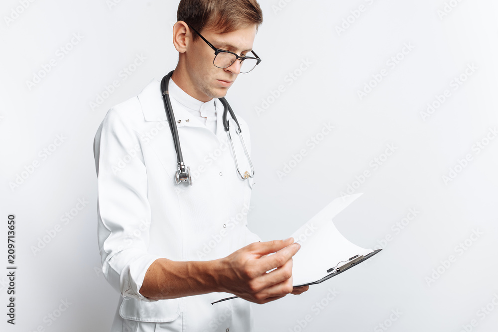 The doctor makes notes in the documents, a young student with a folder in his hands, on a white background The doctor makes notes in the documents, a young student with a folder in his hands, on a white background