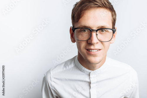 Portrait of young attractive guy in glasses, in white shirt, isolated on white background, for advertising, text insertion