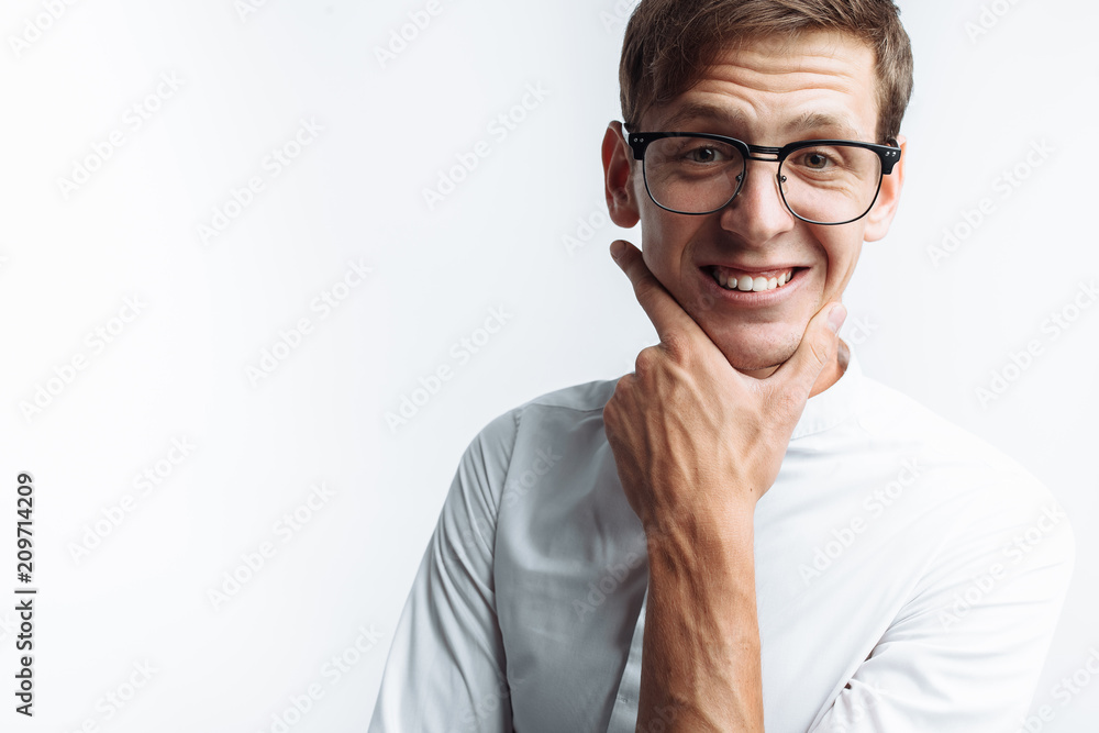 Portrait of young attractive guy in glasses depicting joy, in white shirt isolated on white background, for advertising, text insertion