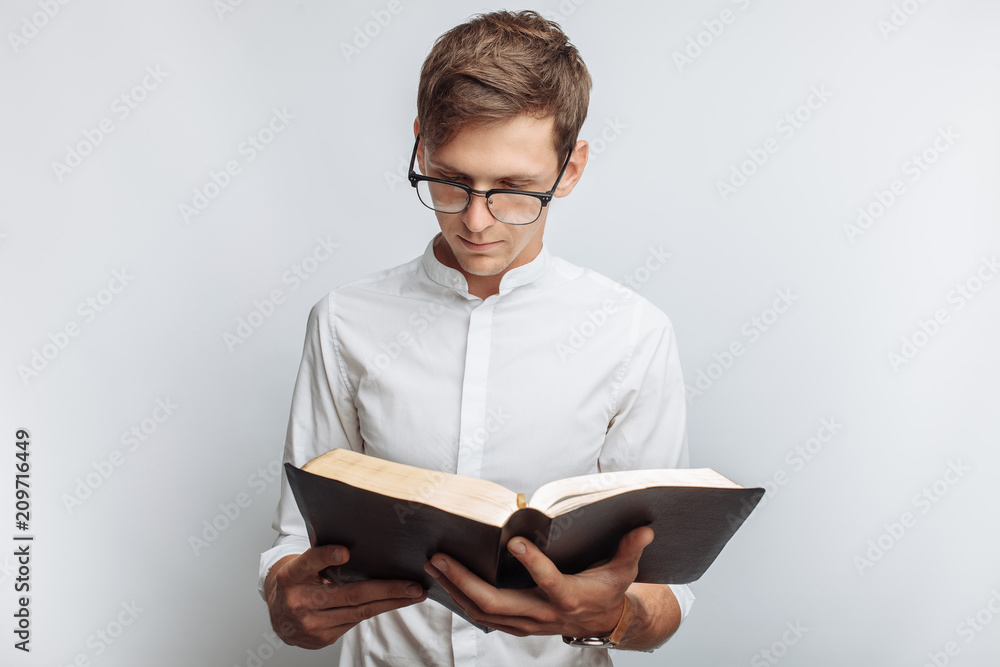 Man reading Bible, white background, book in hand close-up Man reading Bible, white background, book in hand close-up