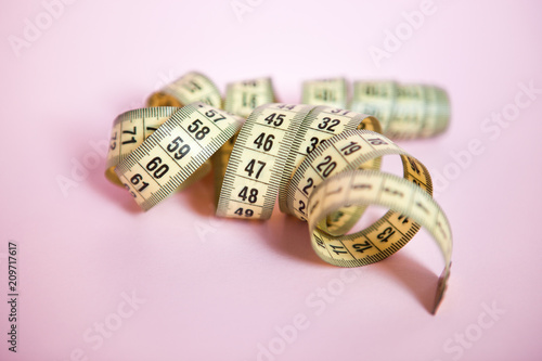Yellow meter measure on pink background, can be used as fitness concept
