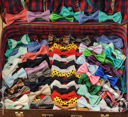 Many colorful beautiful bow ties in an open suitcase
