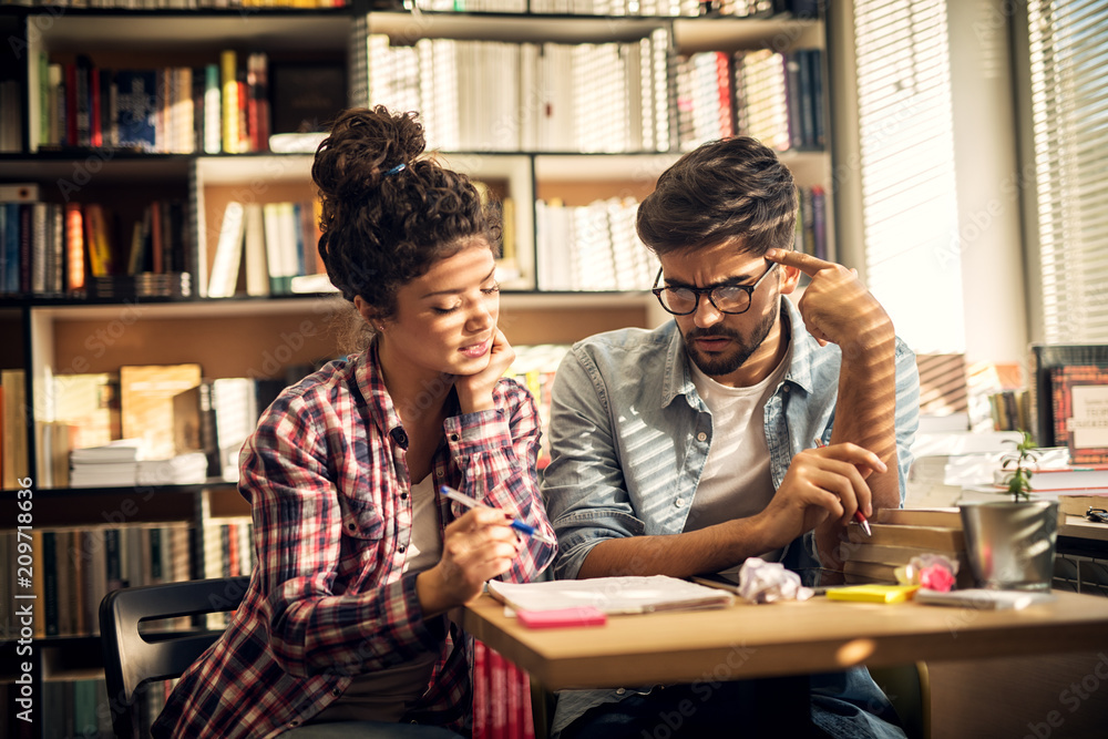 Two young students are having a problem while solving difficult school task they have and are brainstorming new ideas on how to realize it. Two young students are having a problem while solving difficult school task they have and are brainstorming new ideas on how to realize it.