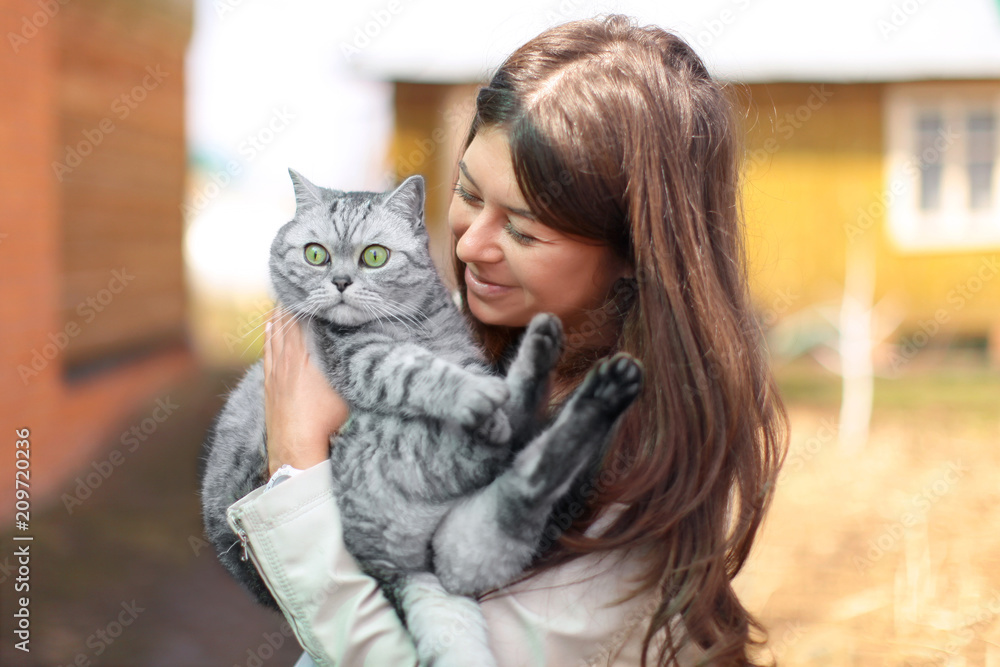 Φωτογραφία young woman hugging her cat breed of a british and happy in a village on nature,