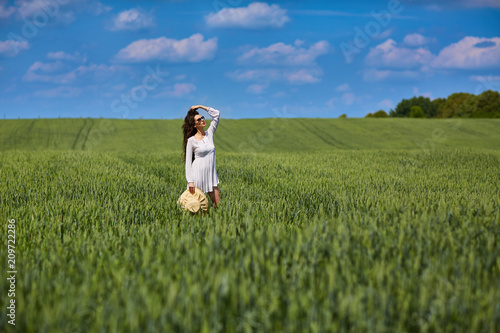 Beautiful girl dressed in white dress standing in the field