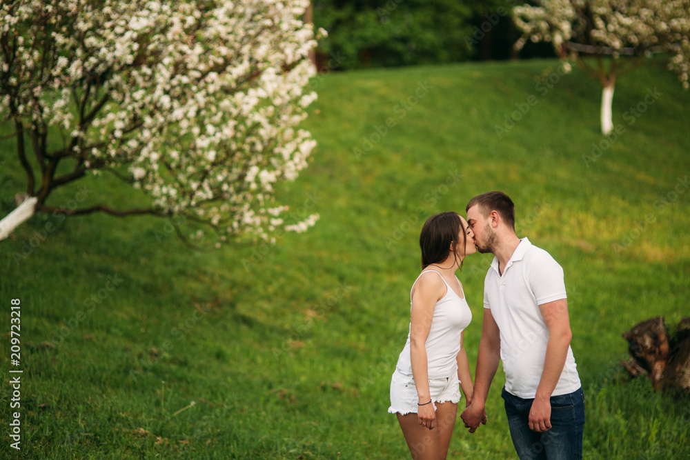 Fototapeta premium Dating in park. Love couple standing together on grass near the lake. Romance and love