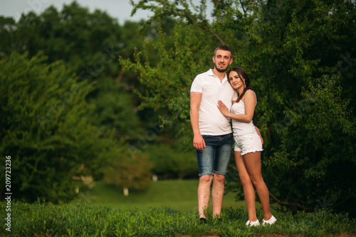 Fototapeta Naklejka Na Ścianę i Meble -  Dating in park. Love couple standing together on grass near the lake. Romance and love