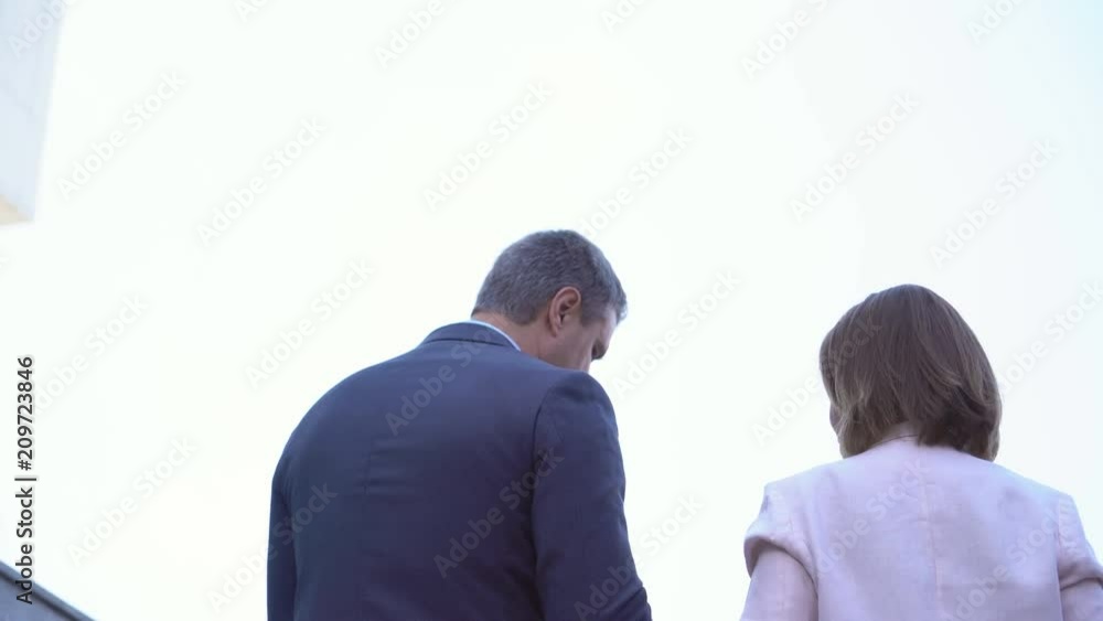 man and woman businessmen walking down the street and discussing a project .. people on the street in the background of an office building. business clothes on actors. Middle-aged businessmen 4K man and woman businessmen walking down the street and discussing a project .. people on the street in the background of an office building. business clothes on actors. Middle-aged businessmen 4K