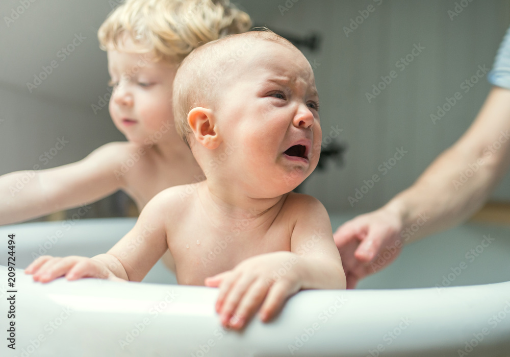 Father washing two unhappy toddlers in the bathroom at home. Father washing two unhappy toddlers in the bathroom at home.