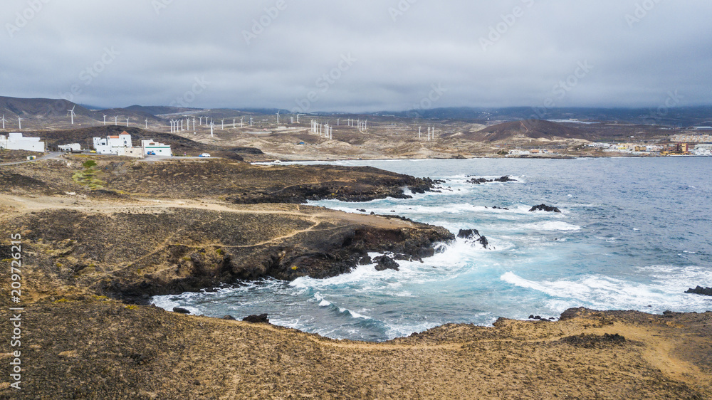 coast ocean waves perfect for surf activity or beautiful scenic landscape. strong ocean power and wind mills in background to produce clean energy electricity