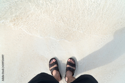 Men wearing sandals are standing on the beach.