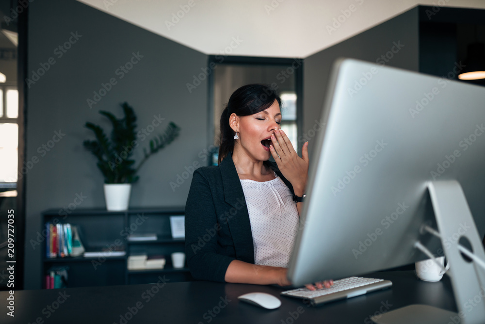 Lovely businesswoman yawning at office desk. Lovely businesswoman yawning at office desk.