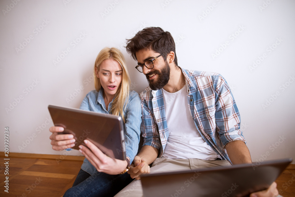 Cute and joyful young couple is leaning against the wall, laughing and holding one arm each up as if they are holding something. Cute and joyful young couple is leaning against the wall, laughing and holding one arm each up as if they are holding something.