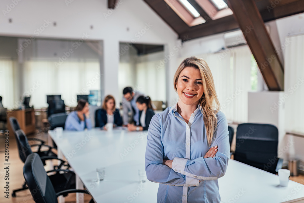 Obraz premium Portrait of successful female entrepreneur, colleagues in the background.