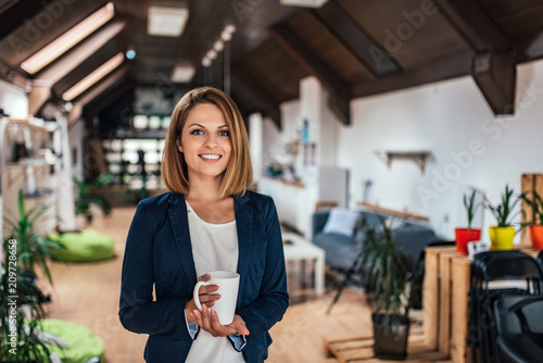 Portrait of a confident young woman holding a mug in a coworking space.
