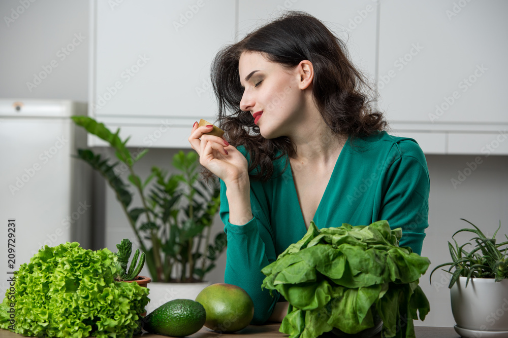 portrait of young woman in a dress eating fruits in the kitchen. Vegetarian concept portrait of young woman in a dress eating fruits in the kitchen. Vegetarian concept