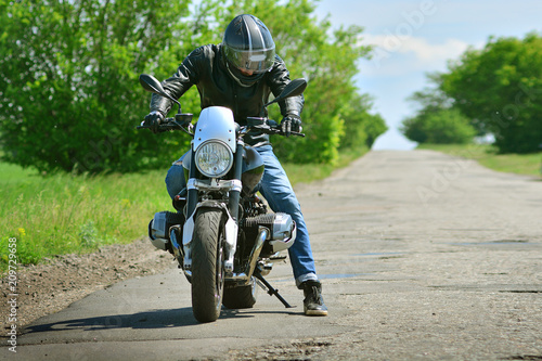Moto biker and his motorcycle on asphalt road