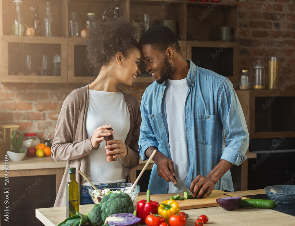 Fototapeta premium Loving african-american couple preparing dinner in kitchen