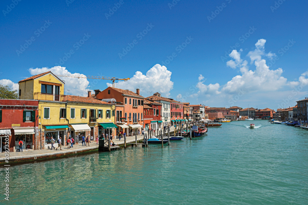 View of buildings, in front of canal, with people and boats in Murano, a nice little town on top of islands near Venice. Located in the Veneto region, northern Italy