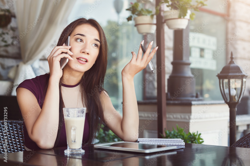 Young businesswoman talking on phone and writing notes