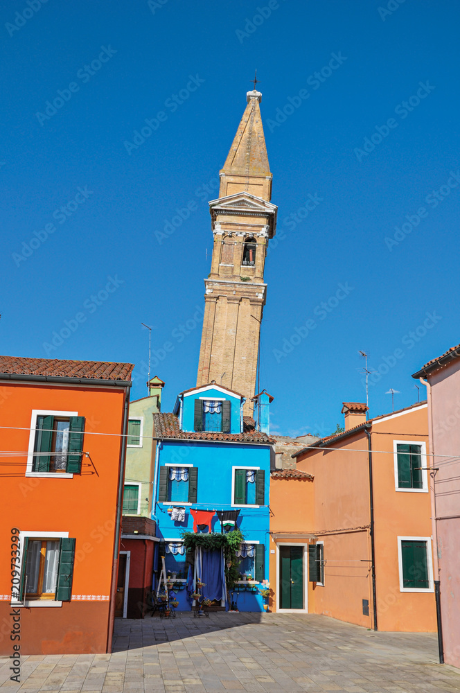Overview of colorful buildings and leaning bell tower in a blue sunny day at Burano, a gracious little town full of canals, near Venice. Veneto region, northern Italy