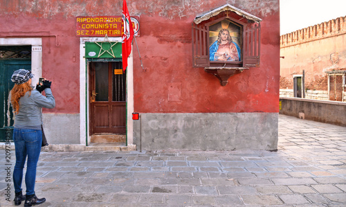 old building facade with entance in local communist party seat and immage of Jesus on the wall sacred and profane photo