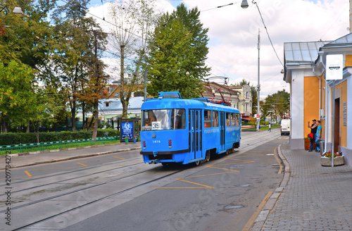 Old blue tram on street of Moscow with blue cloudy sky and historical old buildings in background 