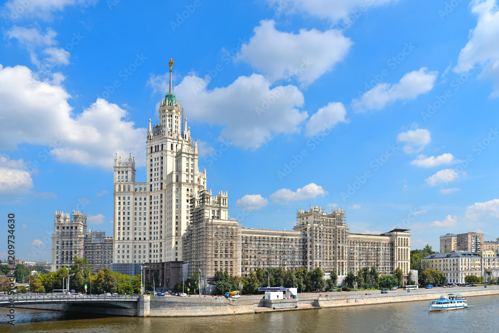 Historical center of Moscow - old colorful building (Stalin skyscraper) and architecture on river with cloudy blue sky. Russia