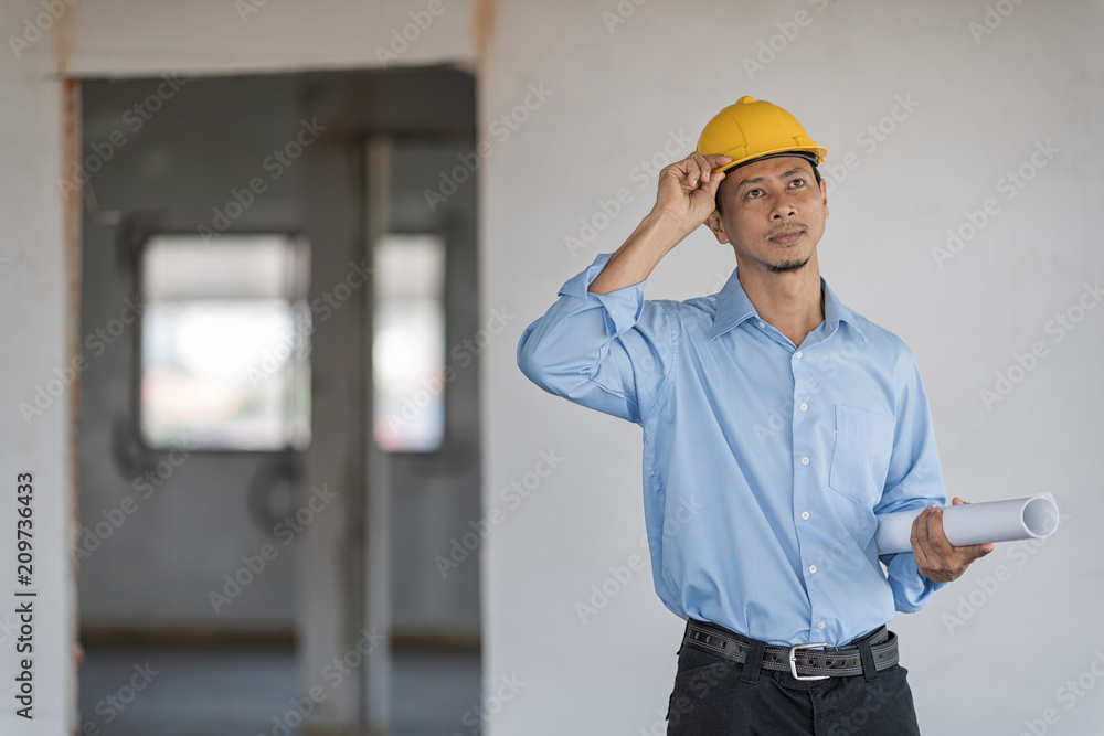 Architect wear yellow helmet is hold blueprint in his hand and looking outside. Architect wear yellow helmet is hold blueprint in his hand and looking outside.