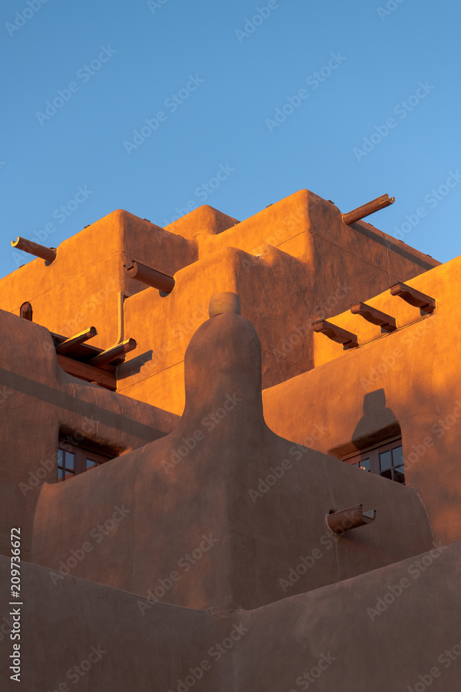 Fototapeta premium Budynek w stylu Adobe pueblo świecący o zachodzie słońca w Santa Fe w Nowym Meksyku