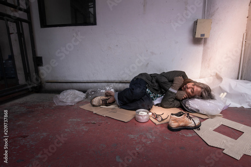 Asian vagrant sleeping on the cardboard on the sidewalk, homeless and hungry man