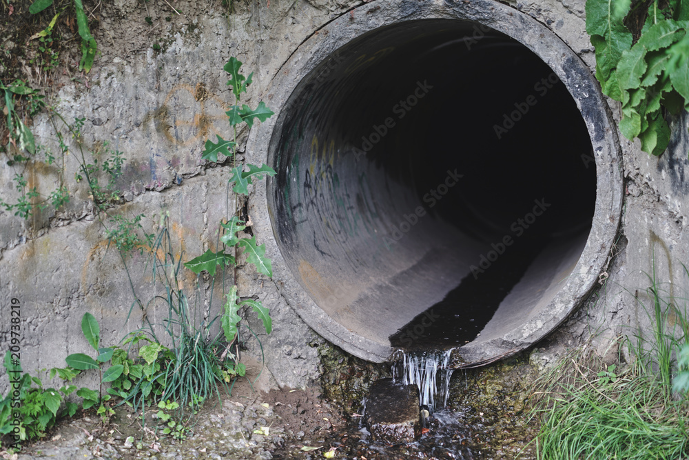 Old concrete and rusty metal, cast-iron drainage pipes in the park. Consolidated wastewater system, leveled in place. Old concrete and rusty metal, cast-iron drainage pipes in the park. Consolidated wastewater system, leveled in place.