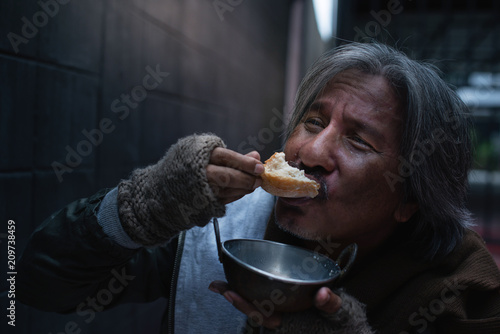 Asian vagrant feel happy with the donated bread and milk.
