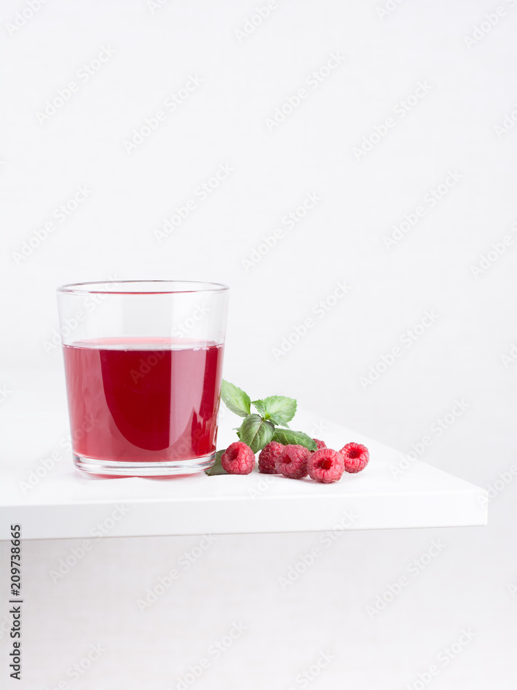Fresh ripe raspberries and raspberry juice in a glass cup on a white background. Close-up, minimal concept of fashion food Fresh ripe raspberries and raspberry juice in a glass cup on a white background. Close-up, minimal concept of fashion food