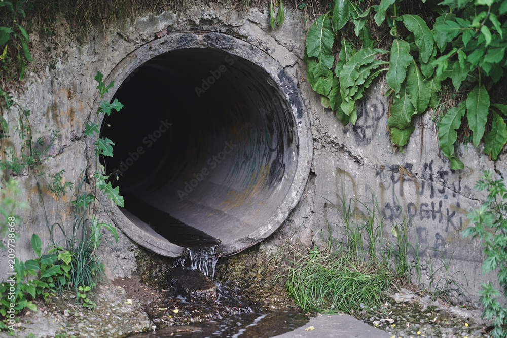 Old concrete and rusty metal, cast-iron drainage pipes in the park. Consolidated wastewater system, leveled in place. Old concrete and rusty metal, cast-iron drainage pipes in the park. Consolidated wastewater system, leveled in place.