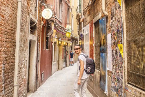 Photography young male tourist in white clothes and sunglasses walking along the street of I