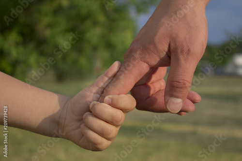 son holds his father's hand, outdoors, close-up © Laura Сrazy