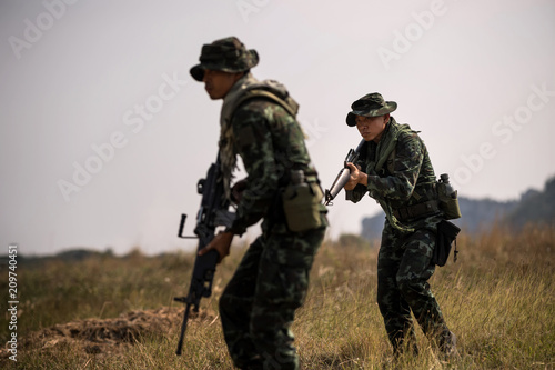 Squad of soldiers patrolling across the deep forest area.