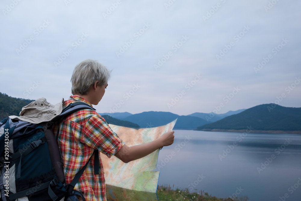 Fototapeta premium Young man trekker use map and enjoy traveling with backpack, hiking concept, travel concept