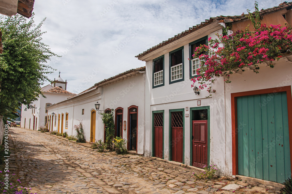 View of cobblestone alley with old colorful houses and vegetation in Paraty, an amazing and historic town totally preserved in the coast of the Rio de Janeiro State, southeastern Brazil