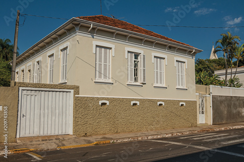 Working-class old house with garage door in an empty street on a sunny day at São Manuel. A cute little town in the countryside of São Paulo State, southeast Brazil